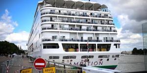 2026年5月13日，乘客站在停靠于法国西南部波尔多港（Bordeaux Port）的巴哈马注册邮轮“雄心号”（Ambition）甲板上。由于船上爆发胃肠道疾病疫情，法国当局要求船上超过1700名乘客与船员暂时留在船内。（图片来源：Christophe ARCHAMBAULT / AFP via Getty Images）