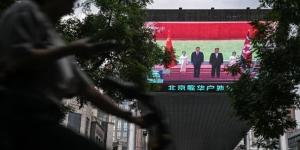 2026年6月8日，一名女子骑车经过北京一家购物中心外的大萤幕，萤幕上正在播放中共党魁习近平与北韩领导人金正恩在北韩会晤的新闻报道。(图片来源：Pedro PARDO/AFP via Getty Images)