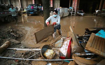 7月9日， 广西省甘塘市一名妇女正在清理洪灾后的房屋。（GREG BAKER / AFP via Getty Images）