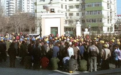 2003年1月17日，数百名工人在北京一处高档住宅区入口处进行封堵，要求支付被拖欠了一年的工资。（图片来源：AFP via Getty Images）