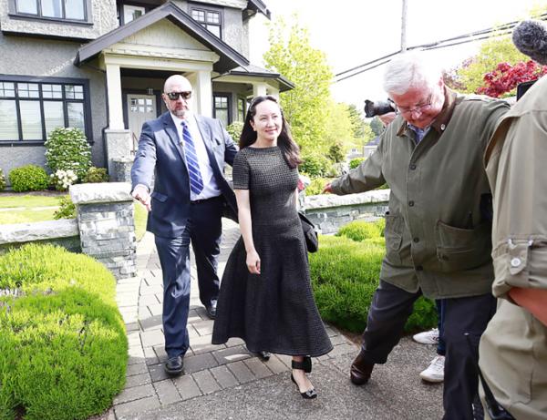 孟晚舟在安保人员陪同下离开住宅，佩戴的黑色电子监控脚环首次被曝光。 (Getty Images)