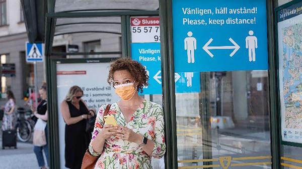 一名女子站在“保持安全社交距离”的牌子旁。(STINA STJERNKVIST/TT News Agency/AFP via Getty Images )