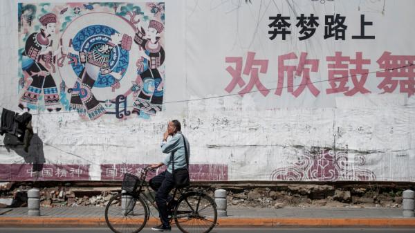 2018年5月29日,辽宁丹东的一位路人骑自行车经过一副中国梦的标语牌。(图片来源:FRED DUFOUR/AFP via Getty Images)