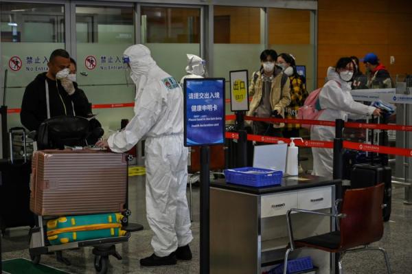 图为2020年3月18日,戴着口罩的乘客抵达上海浦东国际机场(图片来源:HECTOR RETAMAL/AFP via Getty Images)