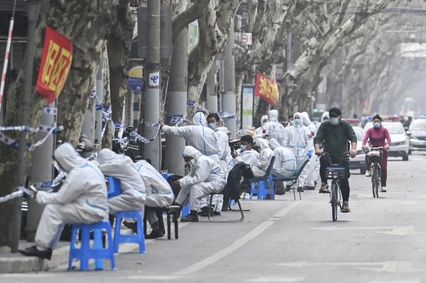 2022年3月14日,身穿防护服的人员在上海一处因疫情封锁的地区工作。(HECTOR RETAMAL/AFP via Getty Images)