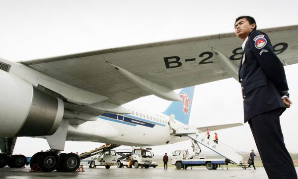 西安机场停机坪上,保安在看着一架中国南方航空公司的飞机。(Peter Parks/AFP via Getty Images)