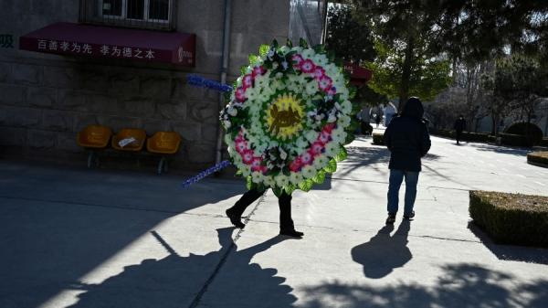 2022年12月22日,中国疫情大爆发期间,北京一个火葬场里持花圈的家属。(图片来源:STF/AFP via Getty Images)