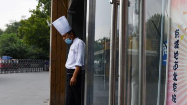 中国大陆餐饮业竞争日趋激烈,2024年第一季度有近46万家餐饮企业关闭。图为2020年9月14日,北京一名厨师站在一家餐厅的入口处等待顾客到来。 (图片来源:GREG BAKER/AFP via Getty Images)