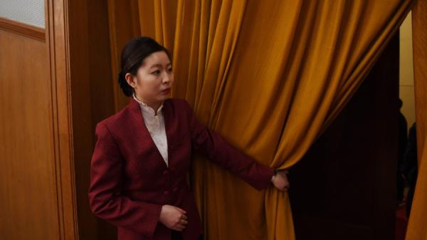 2018年3月3日,在北京大会堂举行的中共政协会议(CPPCC)开幕式上,一名女性工作人员拉着幕布。(图片来源:GREG BAKER/AFP via Getty Images)