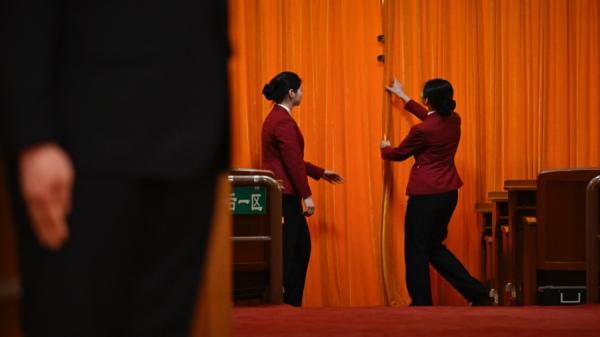 2024年3月5日，在北京人民大会堂举行的全国人民代表大会开幕典礼上，工作人员的在拉上大厅入口处帷幕。（图片来源：Getty Images）