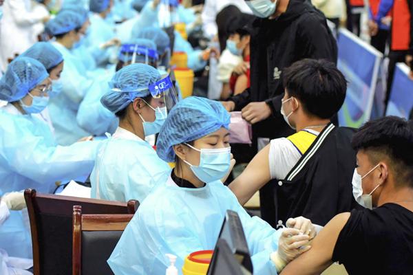 2021年3月30日，在中国山东省青岛市的一所大学内，医务人员正在为学生注射疫苗。（STR/AFP via Getty Images）