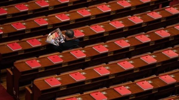 2026年3月12日，在全中共国人民代表大会闭幕式前，一名代表正在北京人民大会堂里阅读关于会议的杂志，桌上可见红色书籍。（图片来源：Getty Images）