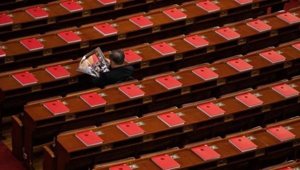 2026年3月12日，在全中共国人民代表大会闭幕式前，一名代表正在北京人民大会堂里阅读关于会议的杂志，桌上可见红色书籍。（图片来源：Getty Images）