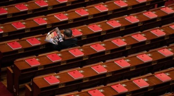 2026年3月12日，在全中共国人民代表大会闭幕式前，一名代表                          正在北京人民大会堂里阅读关于会议的杂志，桌上可见红色书籍。                            （图片来源：Getty Images）