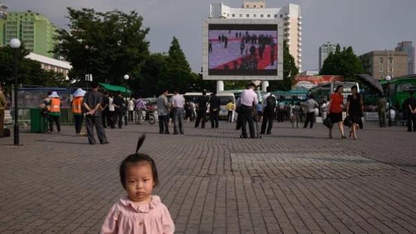 2019年6月21日,在平壤中央火车站外的一处公共广场上,人们正在观看电视新闻播报中共党魁习近平访问平壤期间与朝鲜领导人金正恩会晤的画面。(图片来源:ED JONES/AFP via Getty Images)