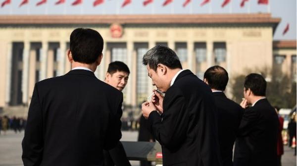 2018年3月19日,在北京人民大会堂举行的第十三届全国人民代表大会第七次全体会议召开前,与会代表们在天安门广场吸烟。(图片来源:Etienne Oliveau/Getty Images)