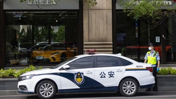 2022年7月1日,一名警察站在上海一家商店前的警车旁。(图片来源:Hugo Hu/Getty Images)