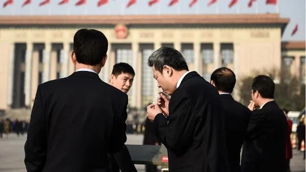 2018年3月19日,在北京人民大会堂举行的第十三届全国人民代表大会第七次全体会议召开前,与会代表们在天安门广场吸烟。(图片来源:Etienne Oliveau/Getty Images)