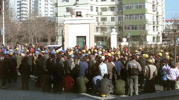 2003年1月17日,数百名工人在北京一处高档住宅区入口处进行封堵,要求支付被拖欠了一年的工资。(图片来源:AFP via Getty Images)