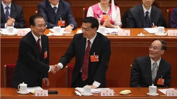 2013年3月5日,时任中共总理温家宝(左)在北京人民大会堂举行的中共全国人大会议开幕式上发表政府工作报告后,与时任中共副总理李克强(右)握手,时任中共副总理王岐山(右)在一旁注视。(图片来源:Feng Li/Getty Images)